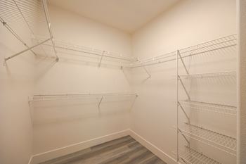a spacious walk in closet in a home with white walls and metal shelves
